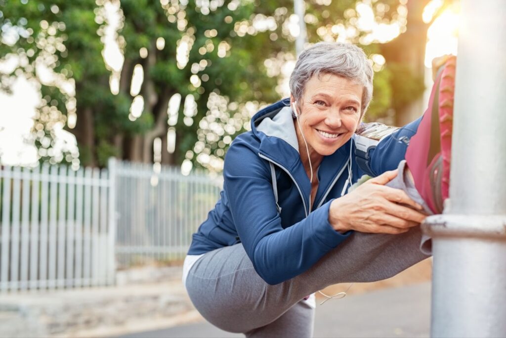 Senior woman performing leg stretches, highlighting post-surgery habits to reduce varicose vein recurrence
