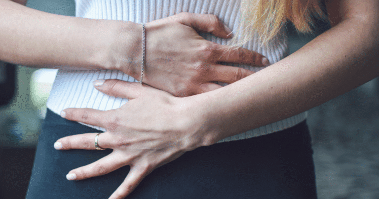 Woman holding her lower abdomen, illustrating discomfort related to pelvic congestion syndrome.