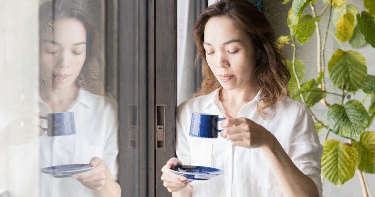 Woman drinking tea while resting at home, representing how fibroids can affect daily comfort and routines.