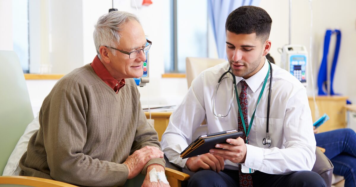 A senior man sits next to his vein specialist to discuss his vascular care