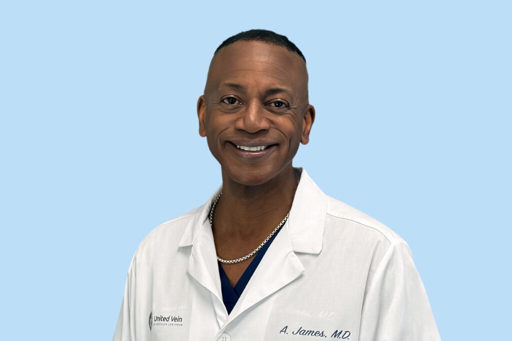 Smiling medical professional in a white lab coat against a light blue background.