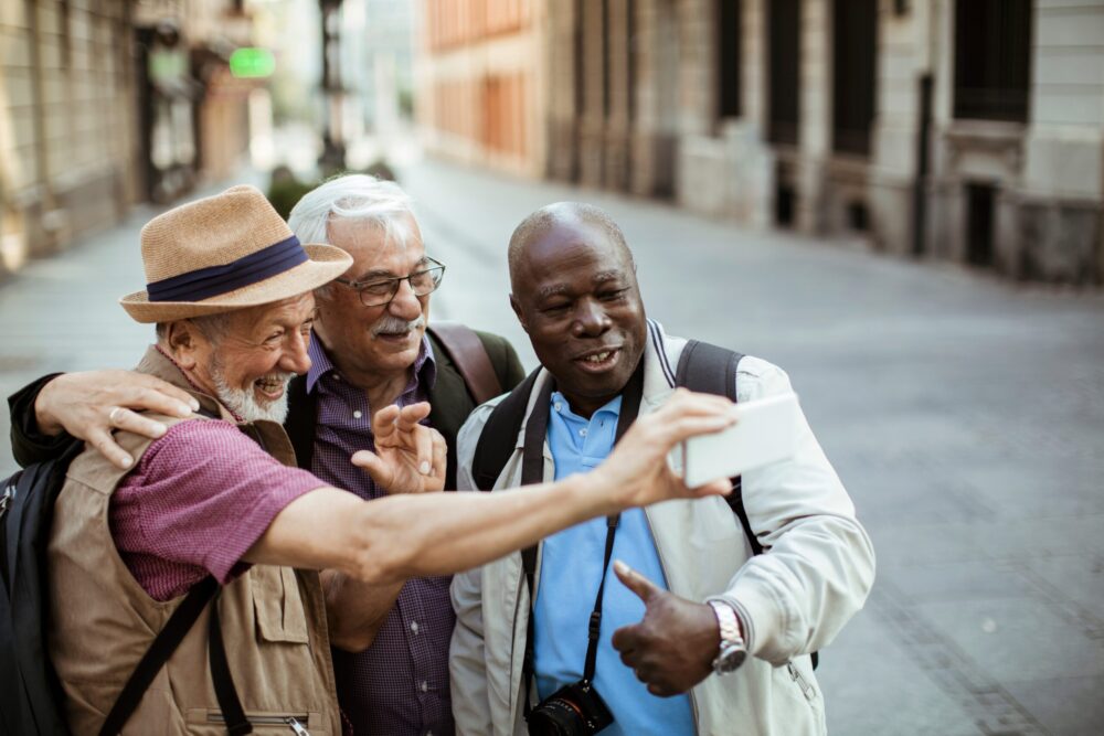 Three men smiling while taking a photo of themselves during travel after VenaSeal