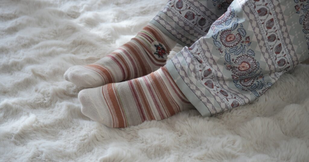 Person wearing socks indoors, highlighting cold feet related to peripheral artery disease symptoms.