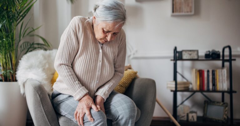 Woman holding her knee in pain, illustrating the progression of chronic knee pain and osteoarthritis