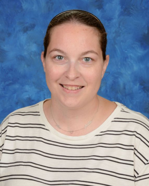 Portrait of educator Kayla Martinez smiling against a blue studio background.