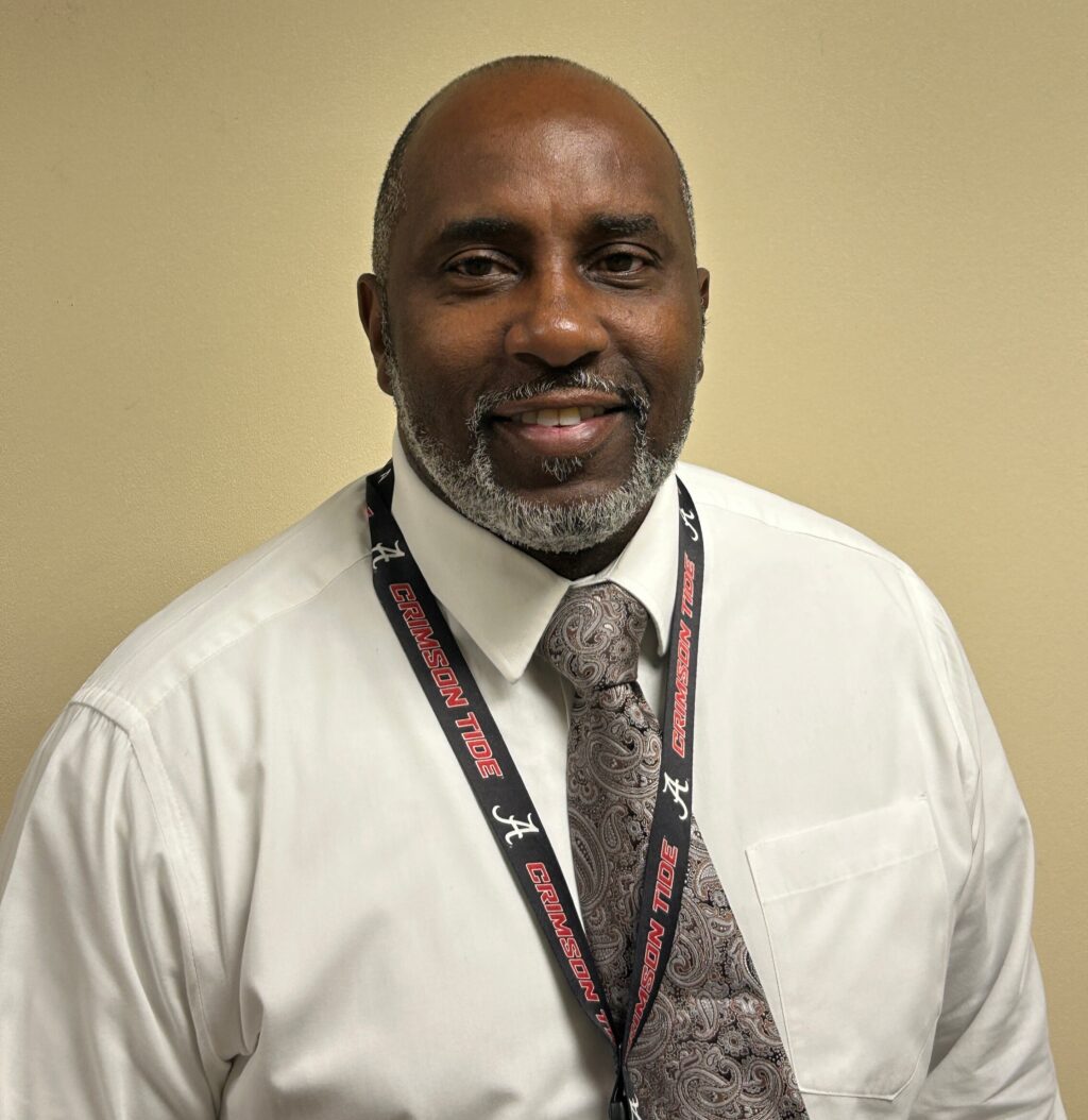 Portrait of educator Derrick Snoddy smiling and wearing a tie and school lanyard.