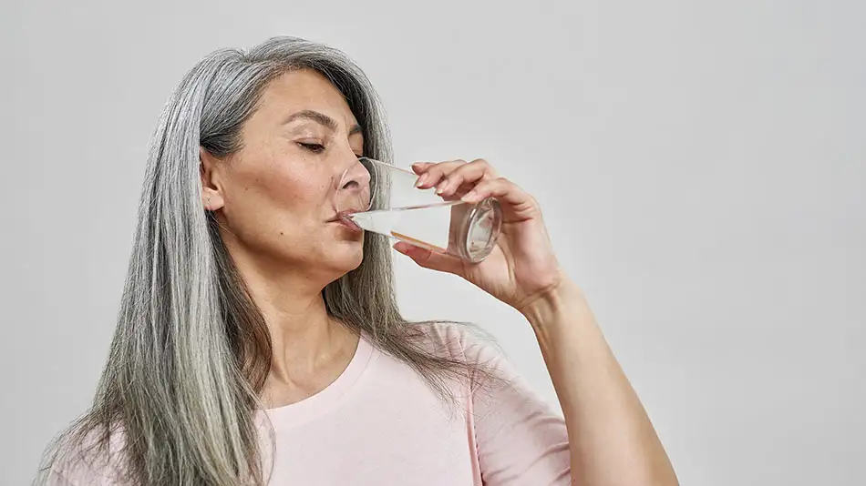 Female woman drinking a glass of water to help keep her veins healthy