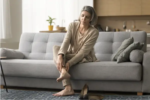 An older woman holding her leg with varicose veins wondering if they are genetic