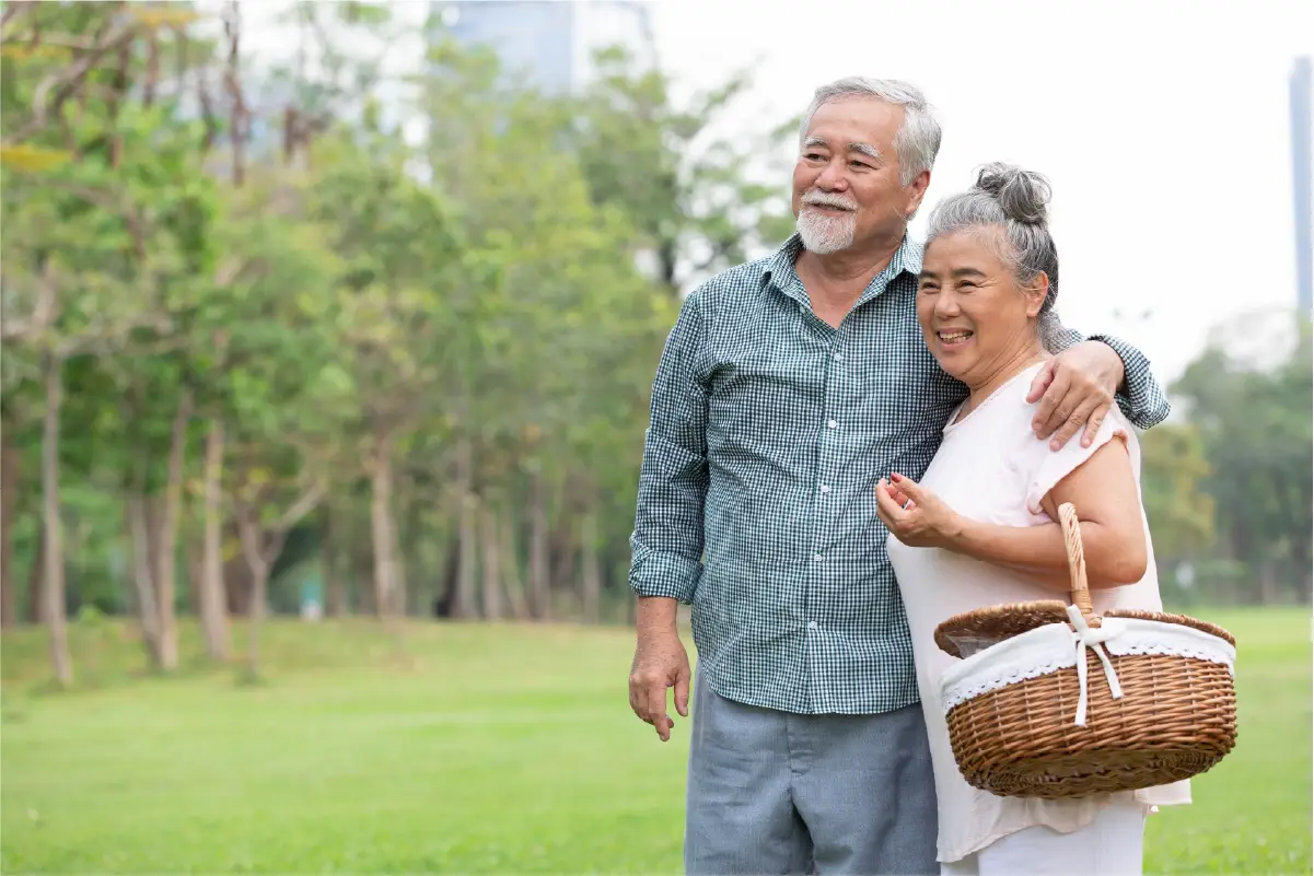 An older male and female stand next to each other, smiling while enjoying a beautiful day at a park in Duluth, GA