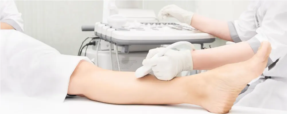 A physician performing a duplex ultrasound on a patient's leg