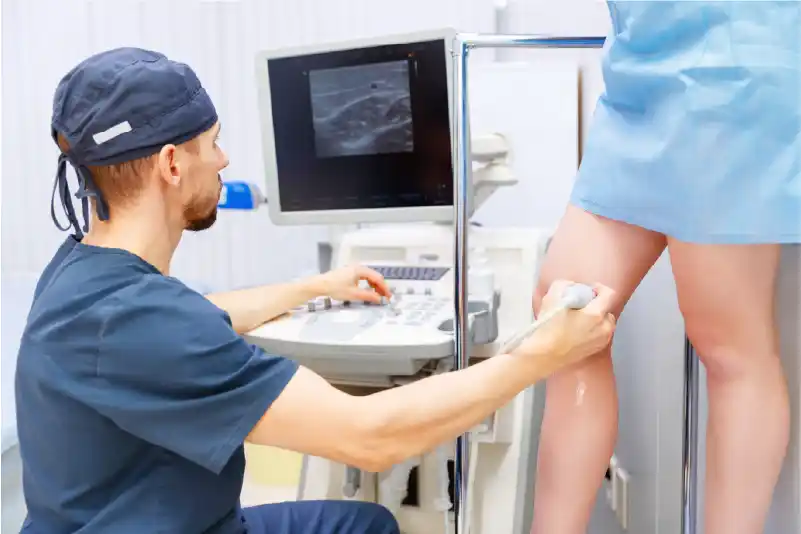 A vein doctor performing a vein screening on a patient's legs