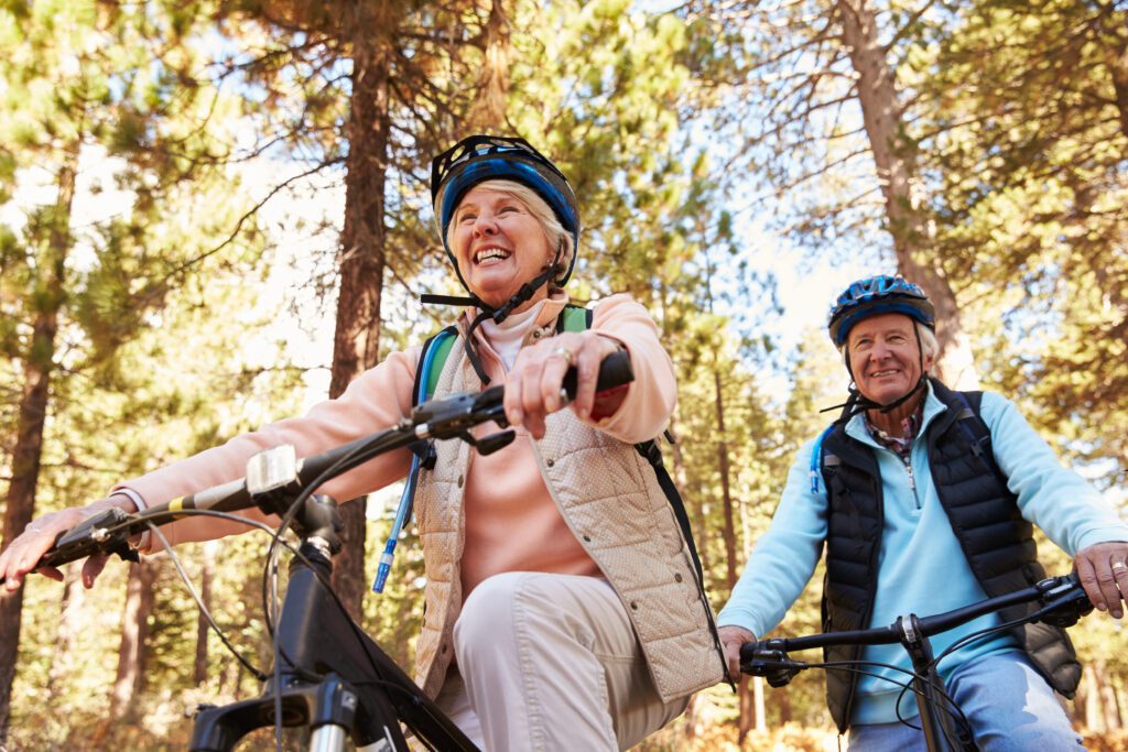A senior couple smiling and riding bikes after vein treatment