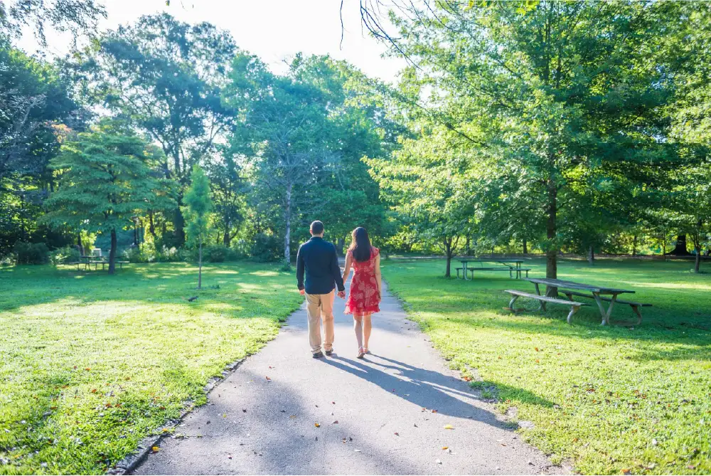 A man and woman walking hand in hand through a wooded park on a sunny day in Atlanta, GA