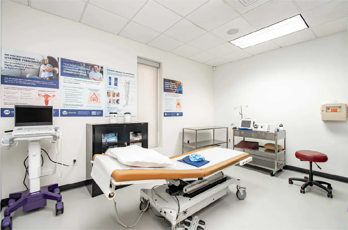 A vein and vascular clinic exam room with a patient table in the middle and various medical equipment against the walls